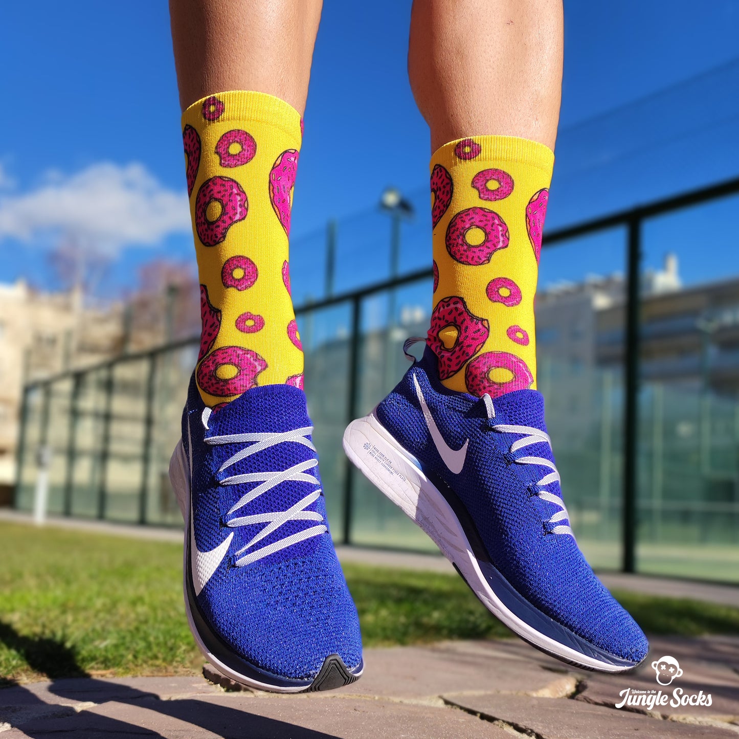 Hombre jugando al padel con calcetines llamativos de donuts amarillos y rosas de JungleSocks